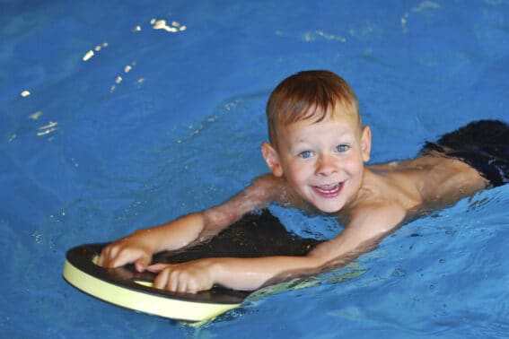 Kind mit Schwimmbrett im Pool